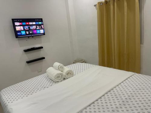 Habitación con 1 cama con toallas y TV. en Plataview Apartahotel apt 4C, en Monte Plata