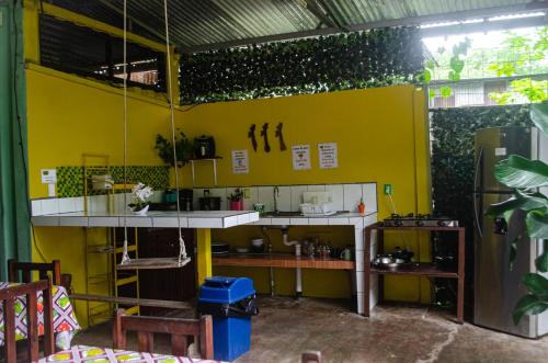 a room with a yellow wall and a kitchen at The Jungle Container in Quepos