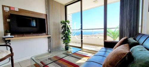 sala de estar con sofá azul y ventana grande en MC Suite Norte - Vista al mar, en Antofagasta