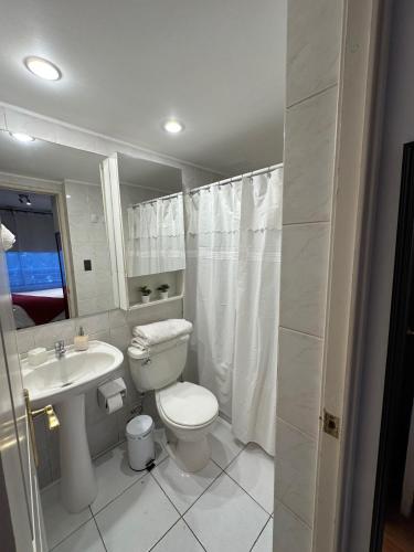 a white bathroom with a toilet and a sink at Depto Las Condes- Est Español in Santiago