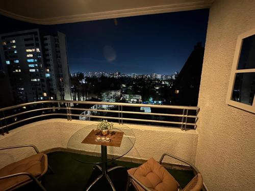 een balkon met een tafel en uitzicht op de stad bij Depto Las Condes- Est Español in Santiago