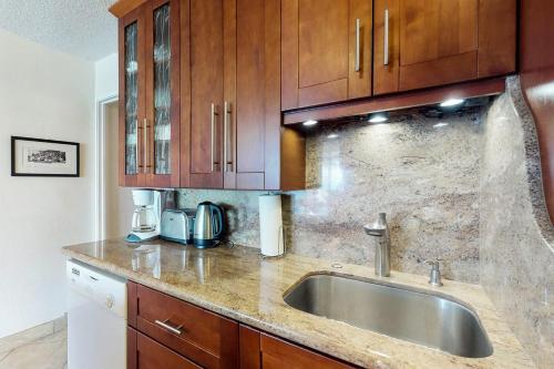 a kitchen with a sink and wooden cabinets at Island Sands Resort Condominiums in Wailuku