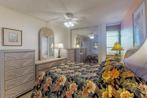 a bedroom with a bed and a dresser and a fan at Island Sands Resort Condominiums in Wailuku