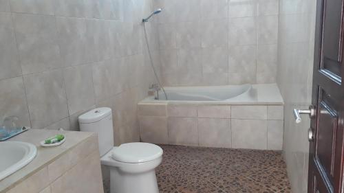 a bathroom with a toilet and a bath tub at Merry's House in Canggu