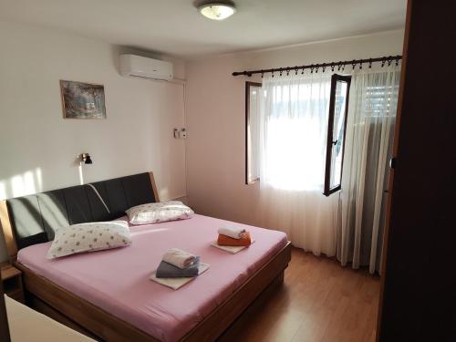 1 dormitorio con cama rosa y ventana en Apartments with a parking space Kampor, Rab - 17873, en Rab