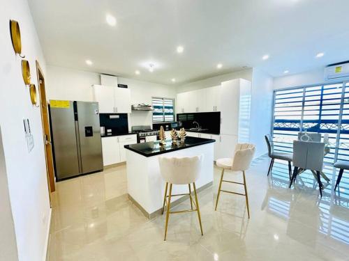 a kitchen with white cabinets and a table and chairs at Modern Oasis By The Waves. in Santa Cruz de Barahona