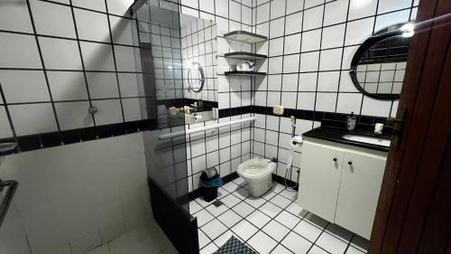 uma pequena casa de banho em azulejos brancos com WC e lavatório. em Sossai Hostel em Vitória