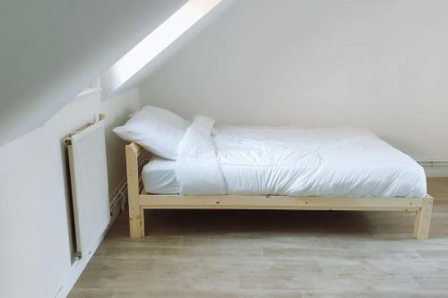 - un lit avec des draps et des oreillers blancs dans l'établissement maison avec jardinet, à Cuincy