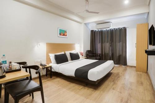 a hotel room with a bed and a desk and a table at Super Townhouse 176 Rajdhani Residency in Surūrnagar