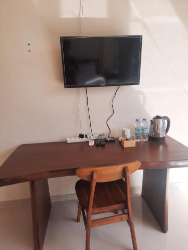 drewnianym biurkiem z telewizorem na ścianie w obiekcie L'JAVAS VILLAS w mieście Kalibendo