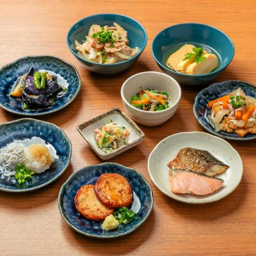 eine Gruppe Teller mit Lebensmitteln auf einem Holztisch in der Unterkunft Kobe Hotel Juraku in Kōbe