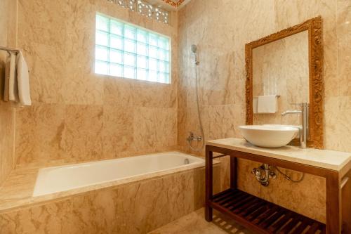 uma casa de banho com um lavatório, uma banheira e um espelho. em Narasoma Homestay & Retreat em Ubud