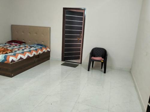 a bedroom with a bed and a chair next to a door at Agarwal Guest House in Naya Raipur