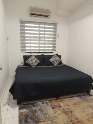 ein schwarzes Bett in einem weißen Zimmer mit Fenster in der Unterkunft PD Seaview Corus Paradise Lagoon in Port Dickson
