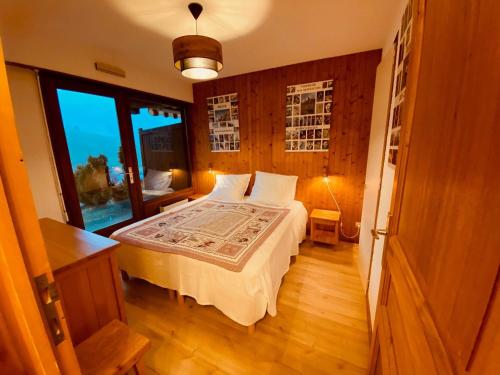 une chambre avec un lit et une grande fenêtre dans l'établissement Appartement cosy avec terrasse, parking et vue montagne à La Clusaz - FR-1-459-220, à La Clusaz