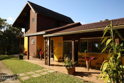 Casa amarilla con puertas de cristal y patio en Pousada nascente das aguas, en Paranaguá