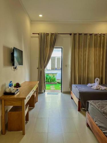 a bedroom with a bed and a desk and a window at ARECA MUINE HOMESTAY in Phan Thiet