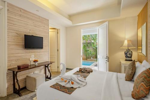 Un dormitorio con una cama y un televisor en una pared. en The Kanjeng Suites Petitenget, en Seminyak