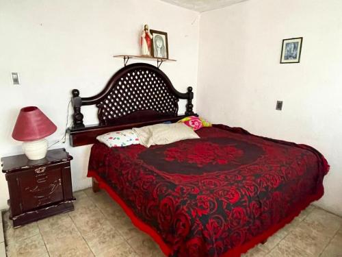 1 dormitorio con 1 cama con manta roja y lámpara en Alojamiento grande, en Uruapan del Progreso