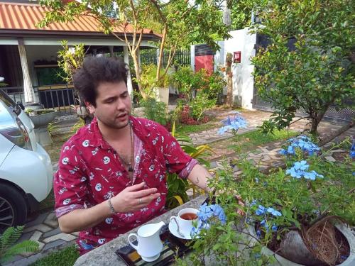 a man sitting at a table with a cup of coffee at Dinu Lanka Resort in Katunayake