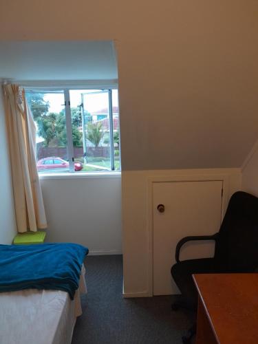 a room with a bed and a window and a chair at Mablet Family Home Stay in Auckland