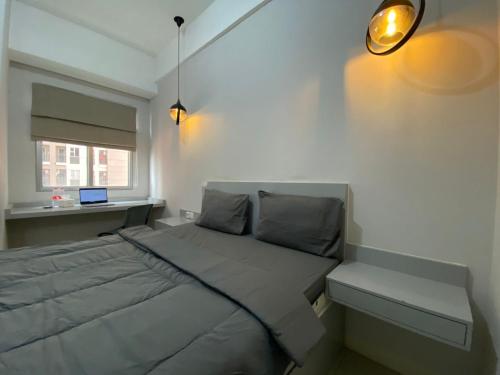 a bedroom with a bed with a desk and a window at Shero Transpark Bekasi in Bekasi