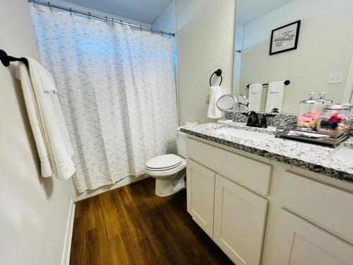 a white bathroom with a toilet and a sink at Daisy's Luxury Home in San Antonio