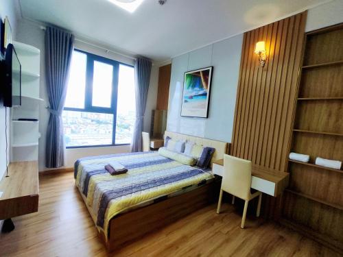 een slaapkamer met een bed, een bureau en een raam bij Chung cư cao cấp Asiana Capella quận 6 in Ho Chi Minh-stad