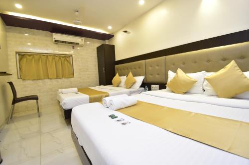 a hotel room with three beds and a chair at Hotel BKC Palace Inn - Jio world convention center and us visa center హోటల్ బి కే సి ప్యాలెస్ ఇన్ in Mumbai