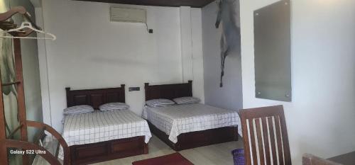 um quarto com duas camas e uma cadeira em Hotel Amendra- A Coastal Escape to Embrace Sea Winds em Matara