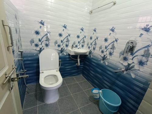 a blue and white bathroom with a toilet and a sink at Sili Homestay in Madikeri