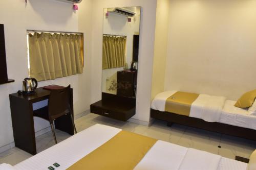 a bedroom with two beds and a desk and a mirror at Hotel BKC Palace Inn - Near US Consulate, Bandra Kurla Complex హోటల్ బి కే సి ప్యాలెస్ ఇన్ in Mumbai