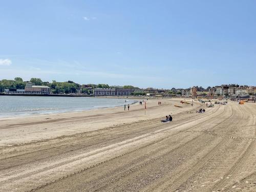 a beach with people sitting on the sand at Fenders in Weymouth