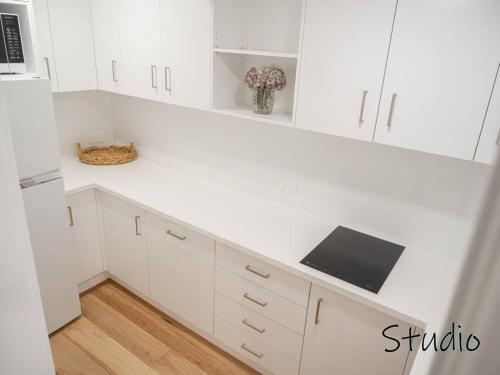 a kitchen with white cabinets and a counter top at Nelson's Oasis By The Beach Studio in Vincentia