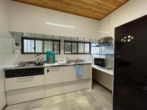 a kitchen with white cabinets and a black refrigerator at Geoparadise Nishiizu in Shizuoka
