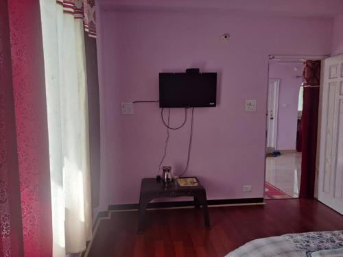 a living room with a tv on a pink wall at Shimla Hills Apartments 2BHK in Shimla