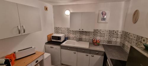 La cuisine est équipée de placards blancs et d'un four micro-ondes blanc. dans l'établissement Le Tassigny, Duplex Superbe Vue sur les Quai, Centre Historique, à Sète