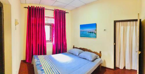 Schlafzimmer mit einem Bett mit roten Vorhängen und einem Fenster in der Unterkunft Villa 163 in Negombo