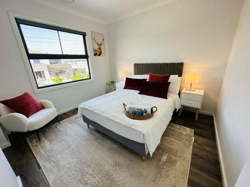1 dormitorio con cama, ventana y silla en Entire house, 5br luxury hideaway, en Narellan