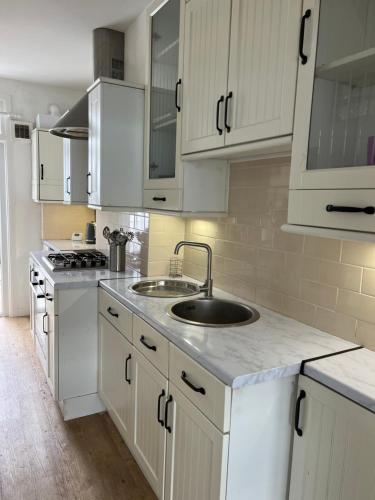 una cocina con armarios blancos y fregadero en Glendale Gardens Apartment en Southend-on-Sea