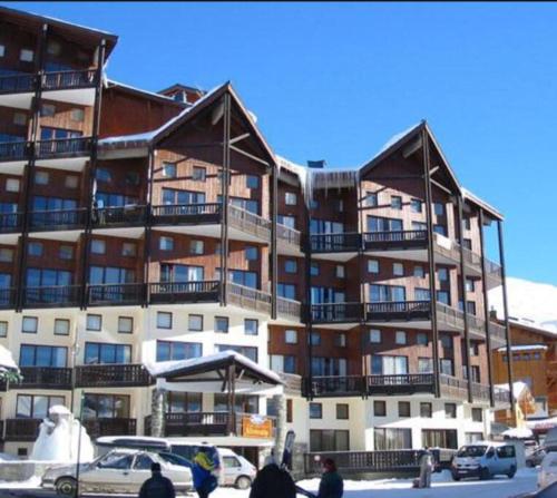 un grand bâtiment avec des voitures garées devant lui dans l'établissement Family Friendly Ski Unit, à Val Thorens