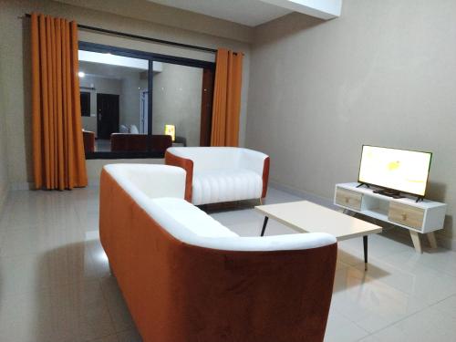 ein Wohnzimmer mit einem Sofa, einem Tisch und einem TV in der Unterkunft Milestone City - Appartements à louer in Antananarivo