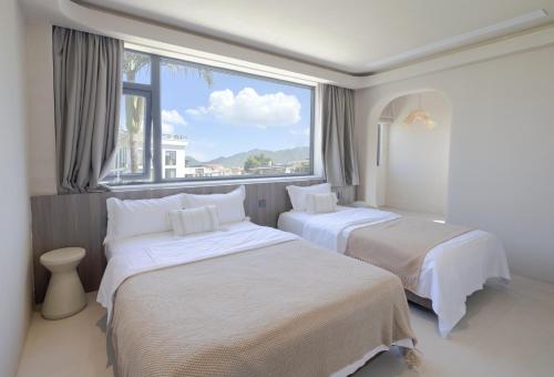 two beds in a room with a large window at Shenzhen Semporna Beach Sea View B & B - 深圳较场尾仙本那沙滩海景民宿 in Shenzhen