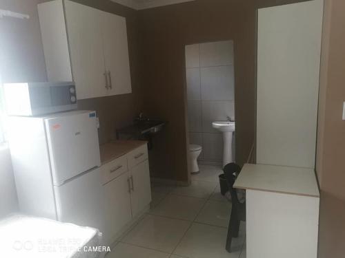 a kitchen with a white refrigerator and a toilet at Kpt property investment in Soweto