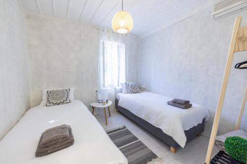 a bedroom with two beds and a chandelier at Theros Cottage - garden & sea breeze in Nafplio