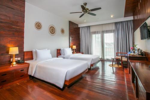 a hotel room with four beds and a ceiling fan at Mera Residence in Siem Reap
