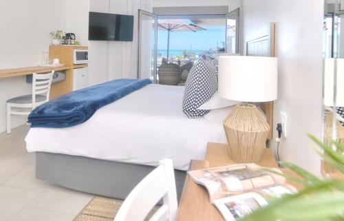 a bedroom with a bed and a table with a lamp at Oceans Guest House & Luxurious Apartments in Struisbaai