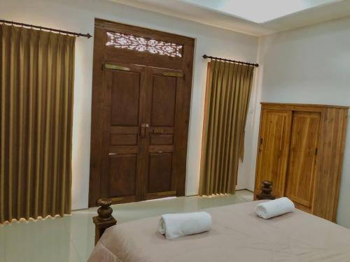 1 dormitorio con 1 cama y puerta de madera en Petak Homestay Ubud, en Penginyahan