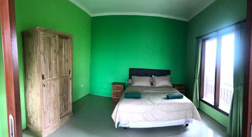 Dormitorio verde con cama y ventana en Petak Homestay Ubud, en Penginyahan