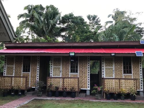 une maison ancienne avec un toit rouge et des arbres dans l'établissement Chloe’s Paradise Hostel, à Batuan